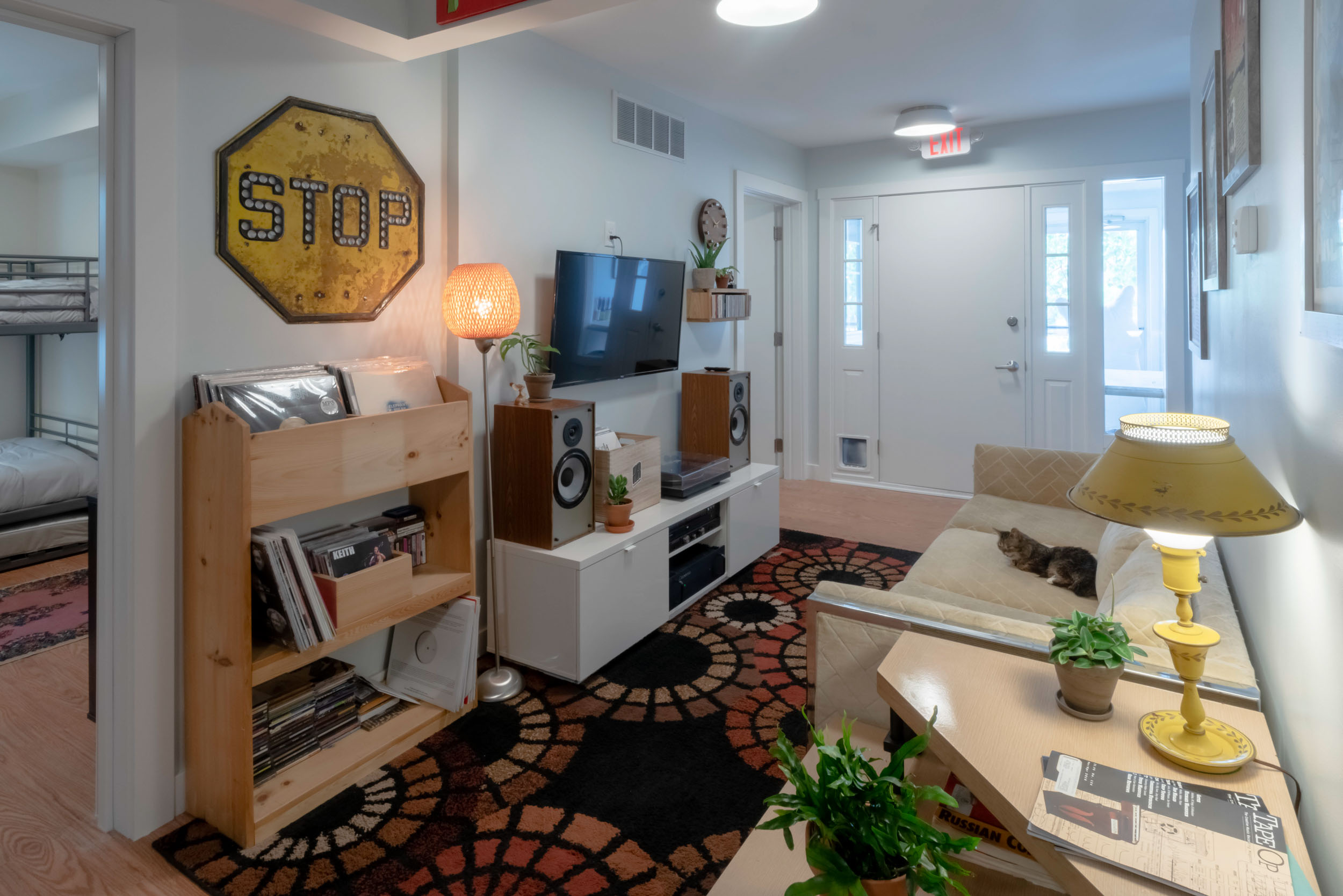 Living space with TV, sofa, bookshelves, and stop sign decor on wall.
